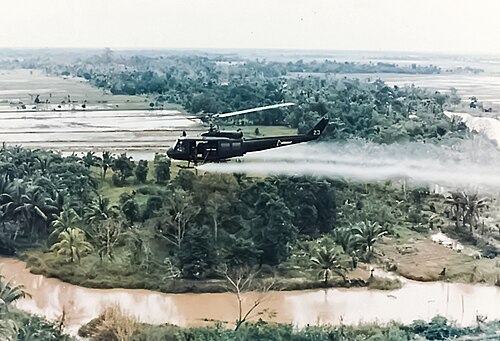 Sebuah helikopter Huey Angkatan Darat AS menyemprotkan Agen Oranye di atas lahan pertanian selama kampanye perang herbisida di Vietnam.