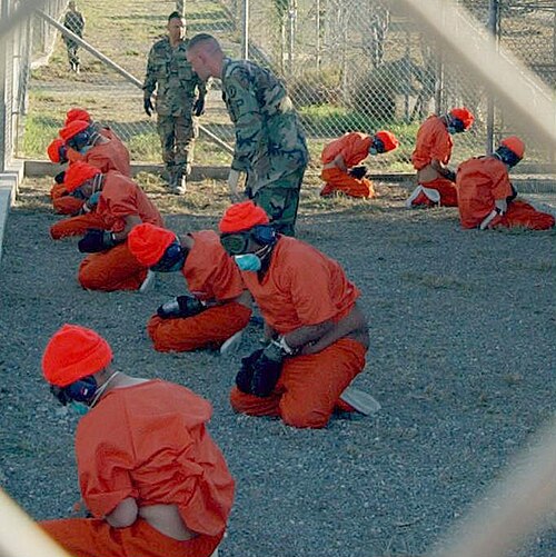 Detainees, shackled and wearing blackout goggles, kneel upon their arrival at Camp X-Ray in Guantánamo Bay, Cuba, on January 11, 2002.