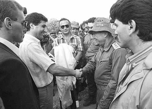 Un Bachir Gemayel sonriente, comandante de las Fuerzas Libanesas, estrecha la mano del jefe del Estado Mayor israelí, Rafael Eitan.